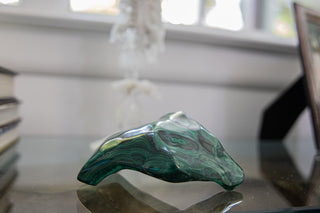 Malachite Gemstone sitting on a class table.