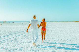 interracial couple running together on the beach in Sarasota Florida female wearing pink bikini male wearing white shirt and pants 