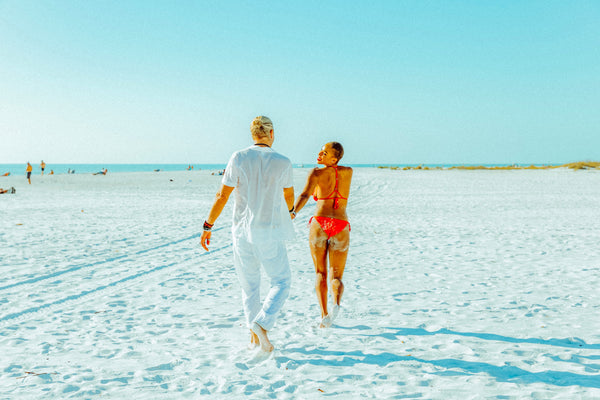 interracial couple running together on the beach in Sarasota Florida female wearing pink bikini male wearing white shirt and pants 