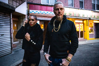 African American female with shaved hair style wearing a black crop top sweater from Zara and black ripped jeans from TopShop. Caucasian model wearing black hoodie with blue jeans from TrueReligion displaying an assortment of gold stainless steel chains