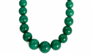 A beaded necklace made of large, smooth, polished green oval beads, arranged in a U-shape against a plain white background.