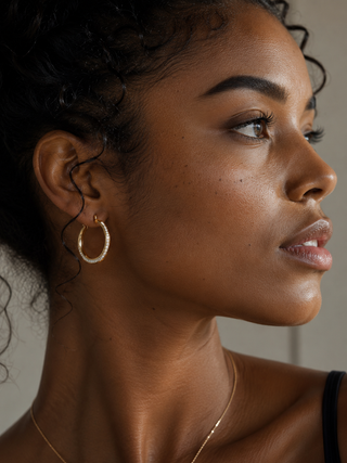 Close-up of a woman wearing gold hoop earrings and a necklace.