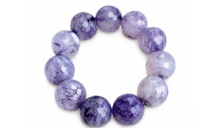 A beaded bracelet made of polished oval gemstone beads in shades of lavender, purple, and white with natural marbled patterns, shown on a plain white background.