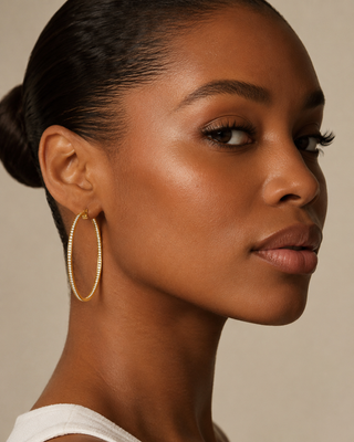 Woman wearing gold hoop earrings against a neutral background The Eva Crystal Hoop Earrings on model