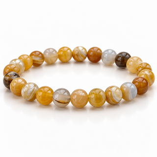 A beaded stretch bracelet made of polished round gemstone beads in shades of golden yellow, amber brown, white, and a few dark brown accents, arranged in a circular shape on a clean white background.