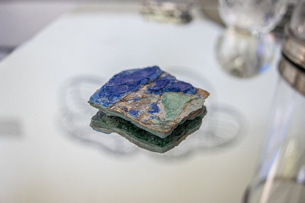 Malachite and Azurite Gemstone Cluster sitting on glass table.
